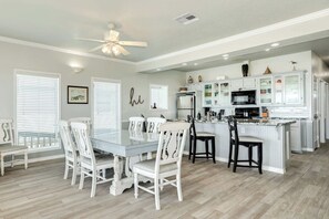 A spacious kitchen with white cabinetry, a dining area with white chairs, and a ceiling fan. - Direct Beach Access Spacious Coastal Retreat (Surfside Beach)