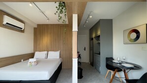A modern hotel room with a bed, bedside table, and a small dining area with chairs and a table. - Vitrali Moema (São Paulo)