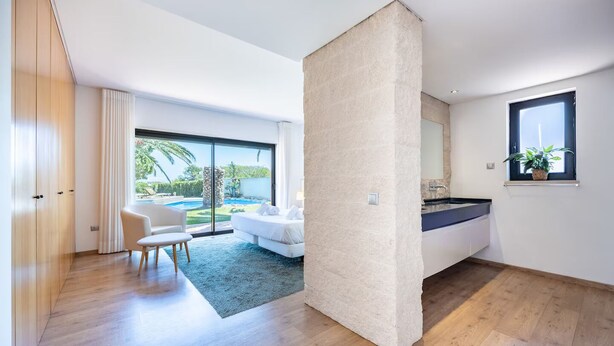 Ein modernes Wohnzimmer mit einem großen Fenster, einem Sofa, einem Couchtisch und Blick auf einen Swimmingpool.