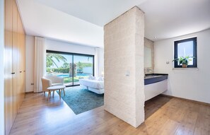 Un salon moderne doté d’une grande fenêtre, d’un canapé, d’une table basse et offrant une vue sur une piscine.