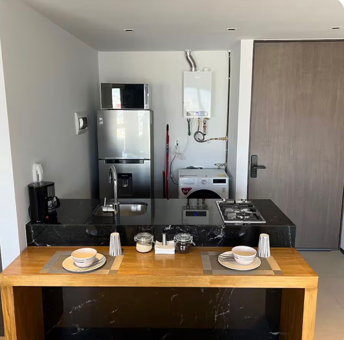 Cozinha compacta equipada com frigorífico, micro-ondas e máquina de café.