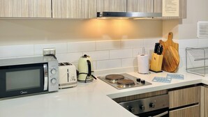 A modern kitchen with wooden cabinets, a microwave, toaster, kettle, and a gas stove. - Apartment in Pucon (Pucon)