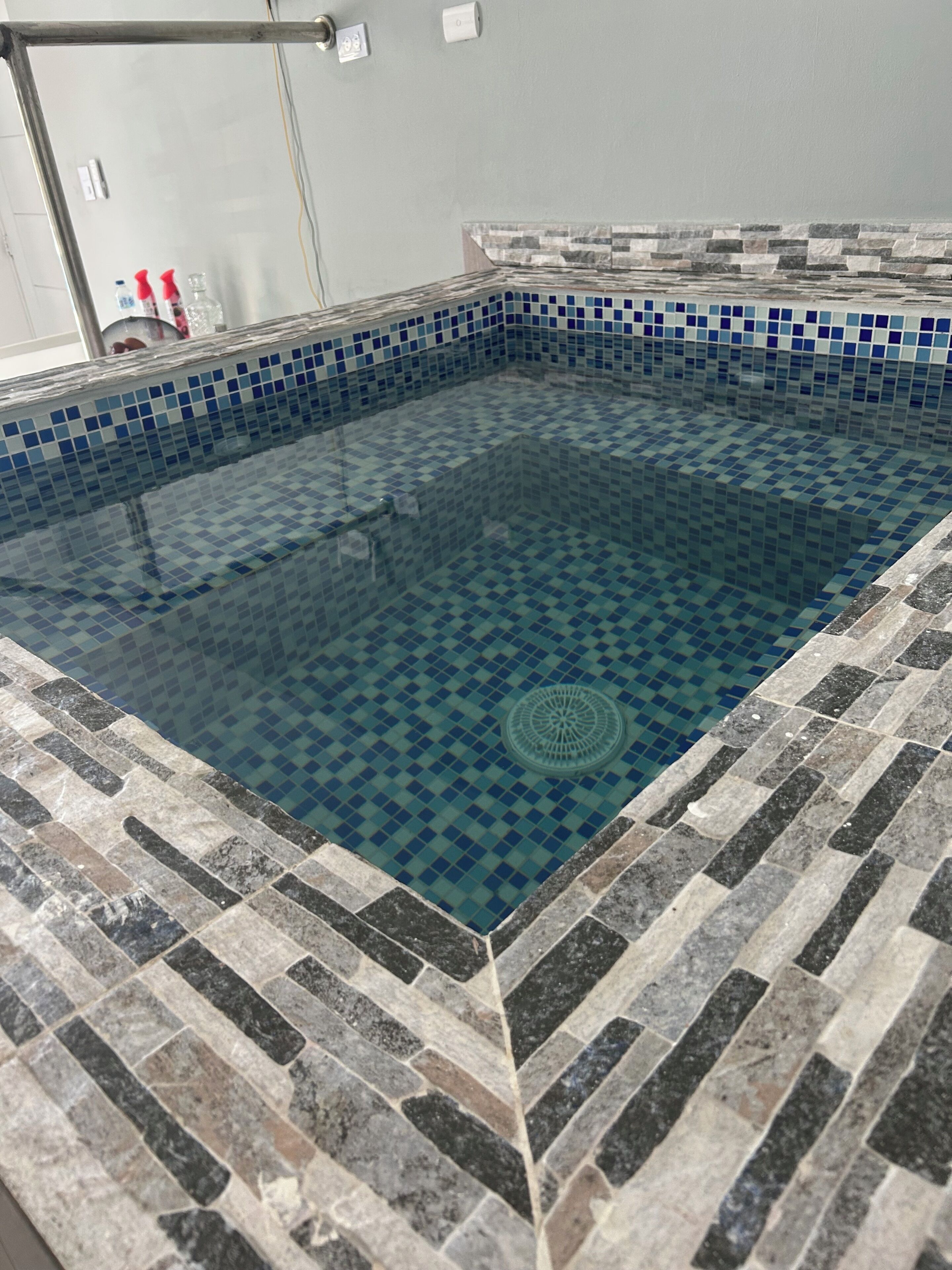 Piscina con diseño de baldosas a cuadros y borde de piedra.