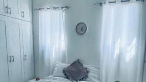 A bedroom with a bed, a bedside table with a plant, a clock on the wall, and a wardrobe. - Your cozy SPA feeling with your in house huge jacuzzi awaits you 400m from beach (la caleta)