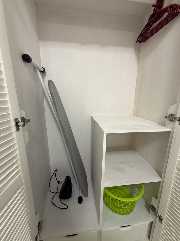 A white storage cabinet with a green basket, a mop, and a broom. - Jagdesh Apartments  (Anna Regina)
