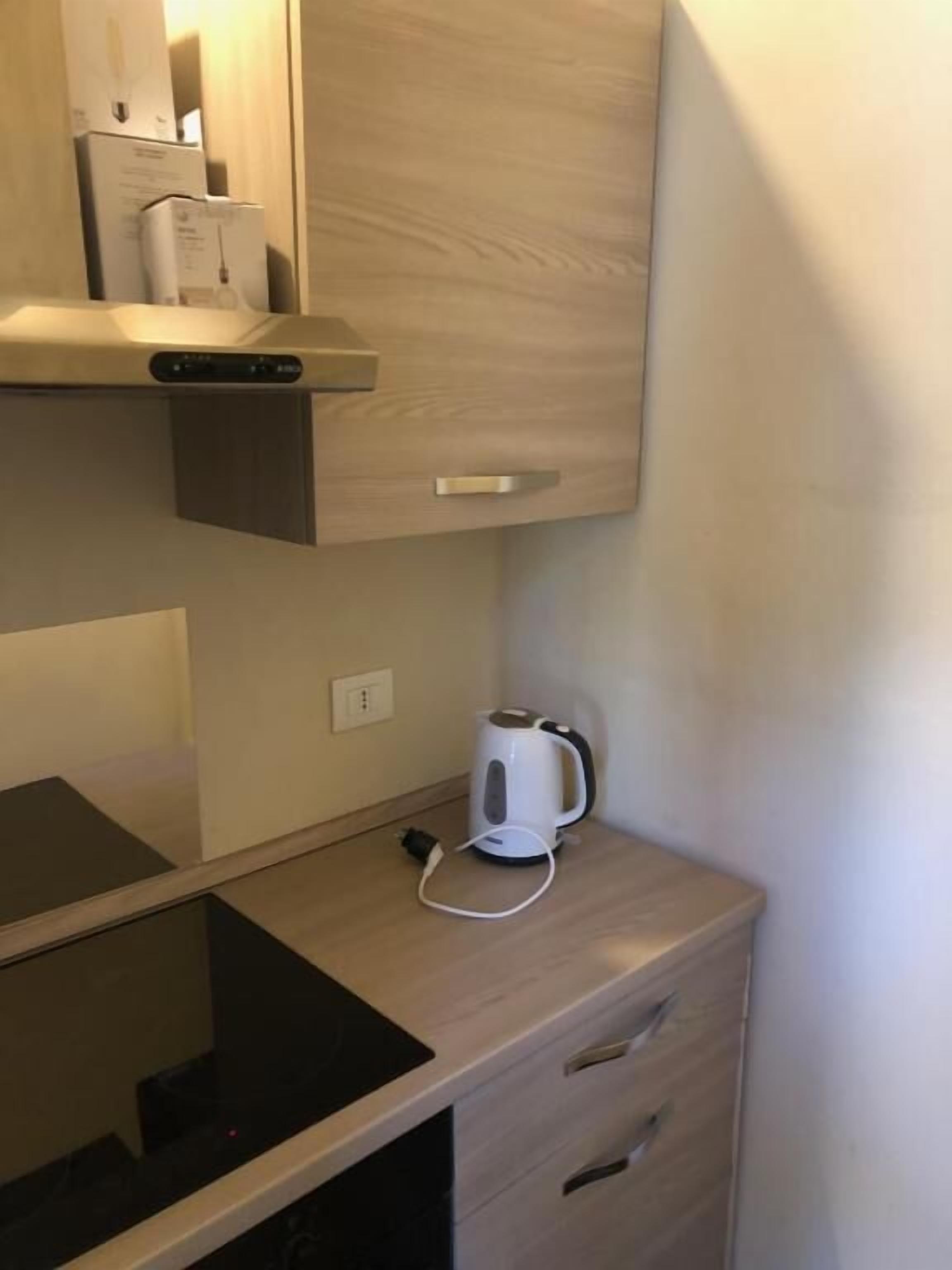 A compact kitchenette with a built-in stove, a kettle, and a small countertop.