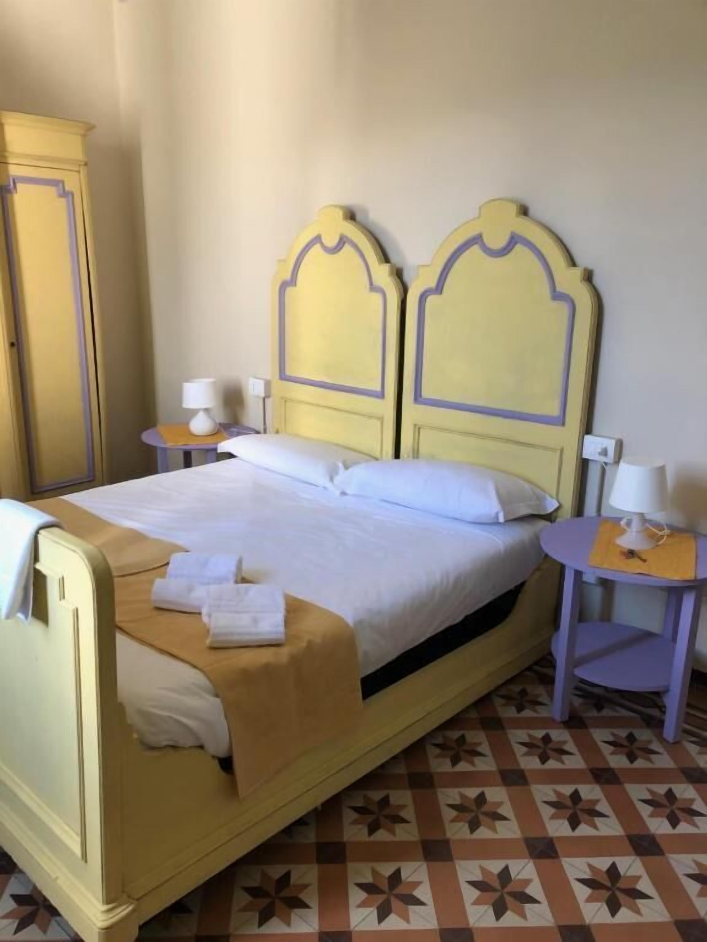 Ein Hotelzimmer mit einem Bett, zwei Nachttischen, einem Kleiderschrank und einem gemusterten Boden.