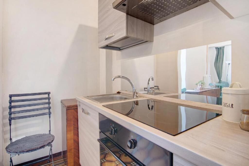 Une cuisine compacte dotée d’un évier à deux bacs, d’un four encastré et d’un pare-feu en miroir.