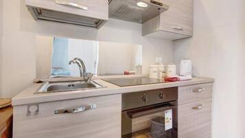 A compact kitchen with a sink, stove, and storage cabinets.