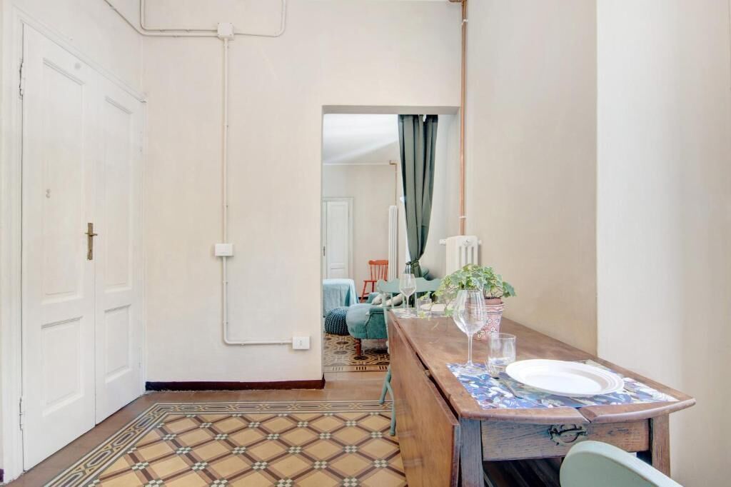 A hallway with a patterned floor leading to a dining area with a table set for two.