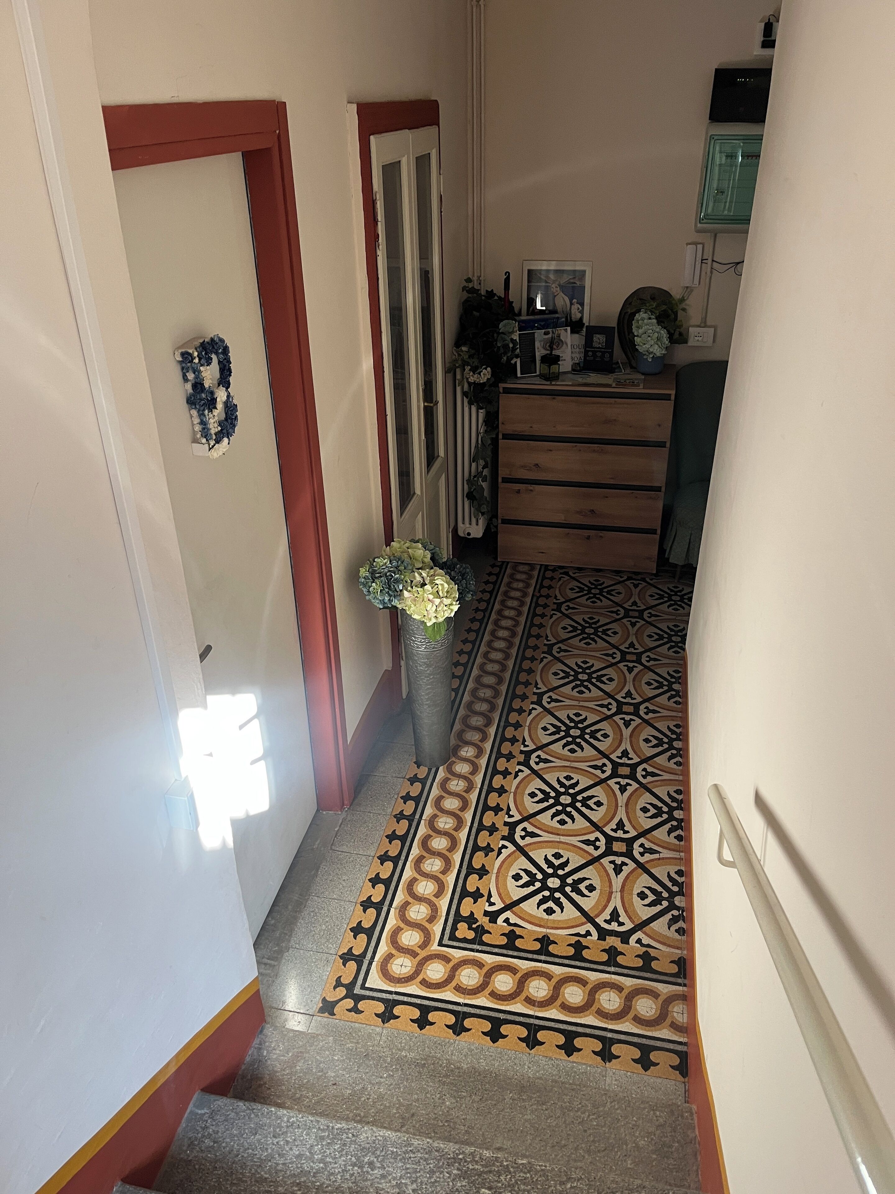Un pasillo con suelo estampado, un aparador de madera y un radiador.