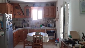 A kitchen with wooden cabinets, a refrigerator, a microwave, and a dining table with chairs. - La Kaz Thomas (Saint-Leu)