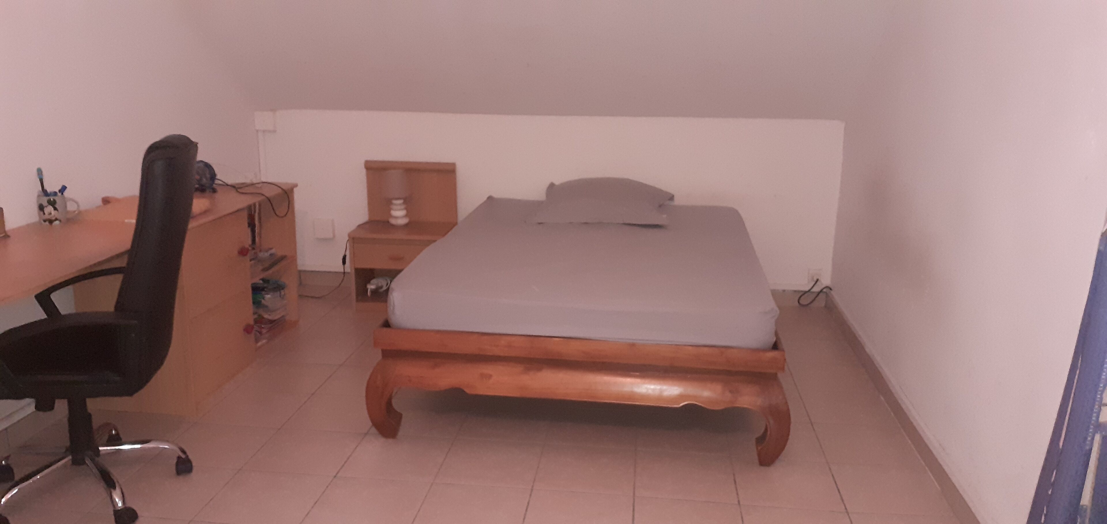 A bedroom with a wooden bed, a desk, a chair, and a nightstand.