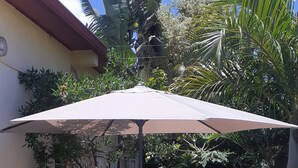A poolside area with two lounge chairs and a table under a canopy, surrounded by tropical plants. - La Kaz Thomas (Saint-Leu)