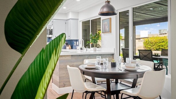 A modern dining area with a round table set for four, surrounded by white chairs. - Desert Oasis 4-bedroom house w/ pool near shopping, Spring Training & more! (Glendale)