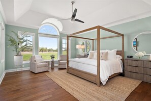Una camera da letto con un letto a baldacchino, una ventola a soffitto, un'ampia finestra e vista sull'esterno.