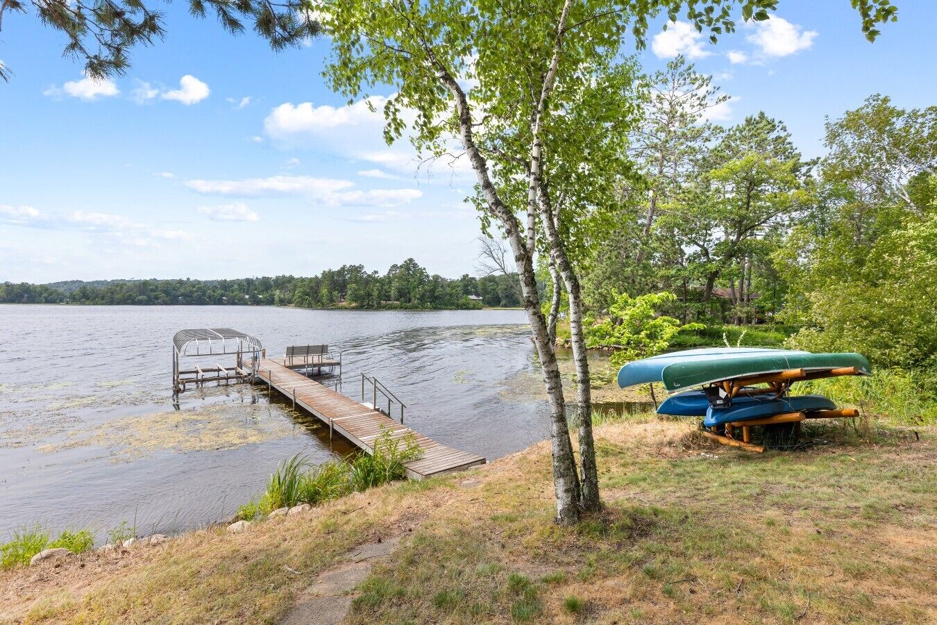 A lakeside dock with canoes and a covered seating area.