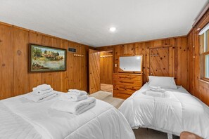 A room with two beds, wooden walls, a painting, a mirror, and a wooden dresser. - Lakefront Brainerd Cabin w Deck, Fire Pit! (Brainerd)