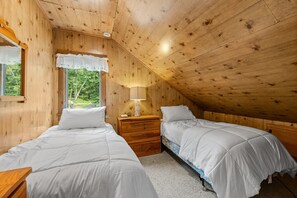 A bedroom with two beds, a window with a white valance, a bedside lamp, and a wooden ceiling. - Lakefront Brainerd Cabin w Deck, Fire Pit! (Brainerd)