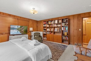 A bedroom with a bed, a bookshelf, a chair, and a television.