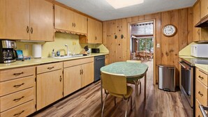 A kitchen with wooden cabinets, a dining table, and a microwave. - Lakefront Brainerd Cabin w Deck, Fire Pit! (Brainerd)