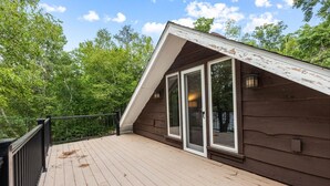 A wooden deck with a railing, a glass door, and a view of trees. - Lakefront Brainerd Cabin w Deck, Fire Pit! (Brainerd)