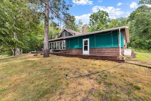 A cabin with a covered porch, a chimney, and a door.