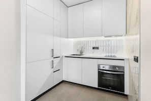 A modern kitchen with white cabinets, a stainless steel oven, and a marble backsplash. - Paraiso Sea Breeze Suite (Adeje)