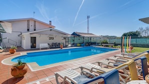 Una piscina con sillas de descanso, un patio y una casa con zona de estar cubierta al aire libre.