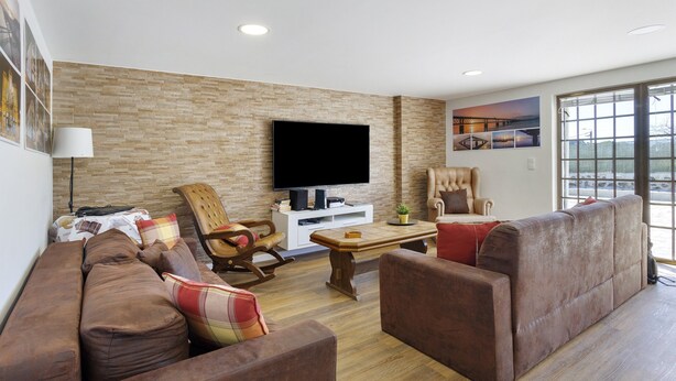 Un salón con televisor de pantalla plana, sofá, mecedora y ventana con vistas.
