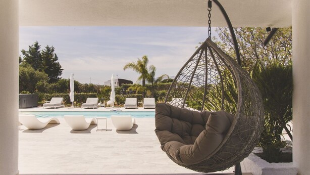 A hanging chair by a pool with lounge chairs and a view of the pool and greenery. - Villa delle Sterlizie by LeDhome (Balestrate)
