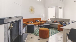 A modern living room with a fireplace, two sofas, ottomans, a coffee table, and a dining area. - Villa delle Sterlizie by LeDhome (Balestrate)