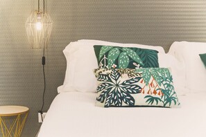 A bed with white bedding, two decorative pillows with a tropical leaf pattern, a small round yellow table, and a hanging light fixture. - Villa delle Sterlizie by LeDhome (Balestrate)
