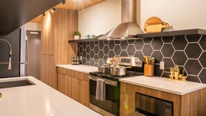 Una cocina moderna con estufa de acero inoxidable, armarios de madera y un salpicadero hexagonal negro.