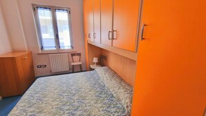 A bedroom with a bed, a chair, a desk, and a radiator. - Blue Bilo with terrace facing the sea and beach (Marcelli)