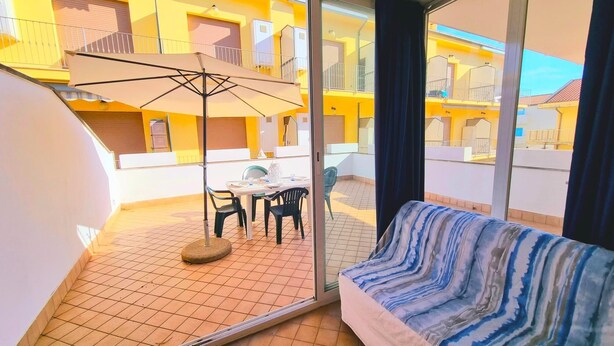 A balcony with a table and chairs, a sofa, and a large umbrella. - Blue Bilo with terrace facing the sea and beach (Marcelli)