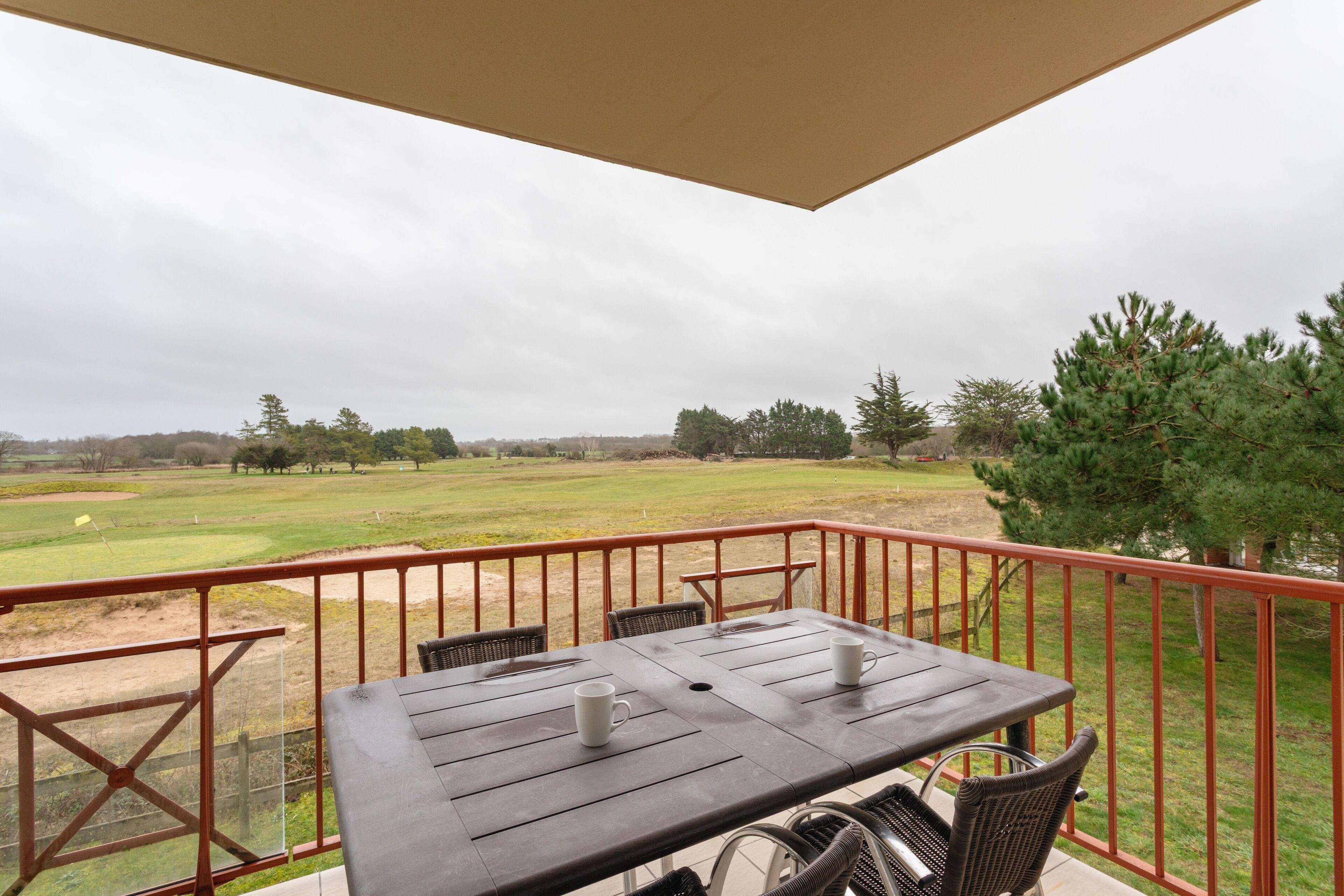 A balcony with a table and chairs overlooking a golf course.