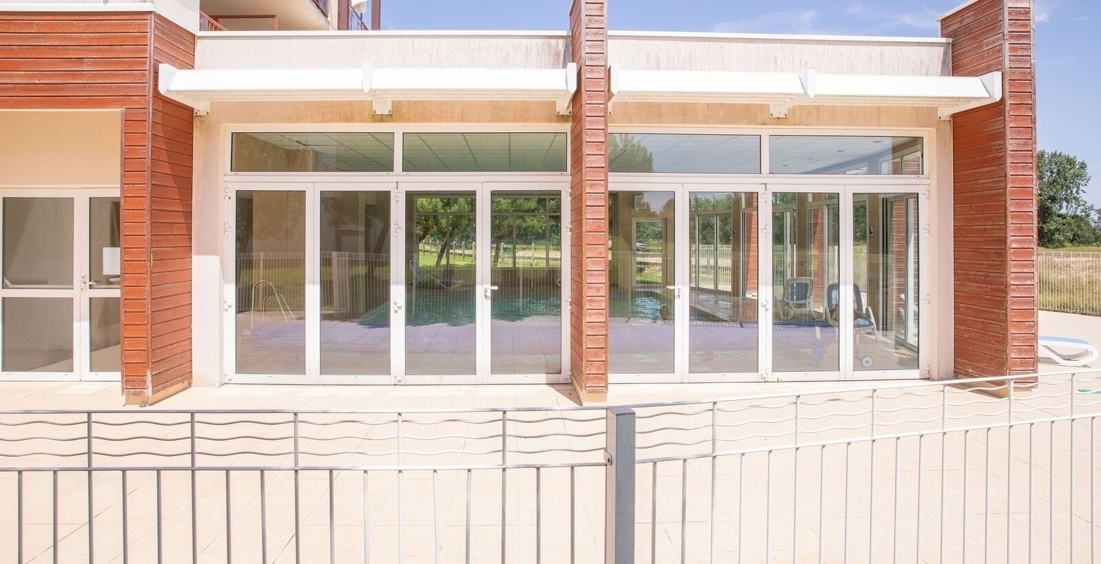 A modern building with large glass windows, a brick facade, and a metal railing in front.