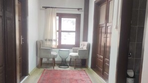Ein Flur mit einem roten Teppich mit Muster, einem Fenster mit Vorhängen und einer Sitzecke mit zwei Sesseln und einem kleinen Tisch.