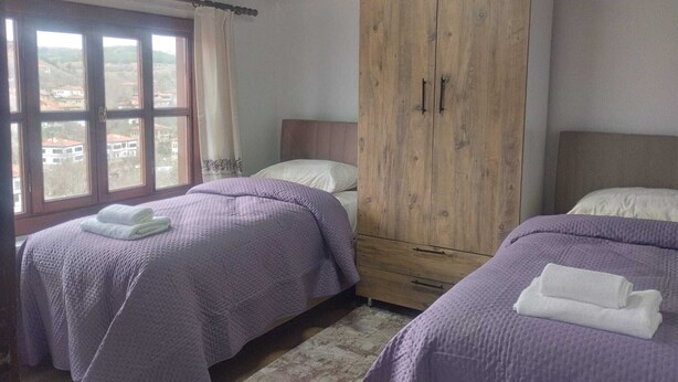 Ein Schlafzimmer mit zwei Betten, einem Holzschrank und einem Fenster mit Vorhängen.