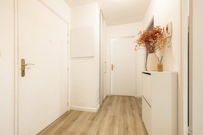 A hallway with white walls, a wooden floor, and a white door with a brass handle.