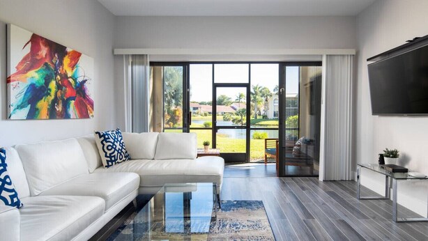 Ein modernes Wohnzimmer mit einem weißen modularen Sofa, einem Glastisch und einem großen abstrakten Gemälde an der Wand.
