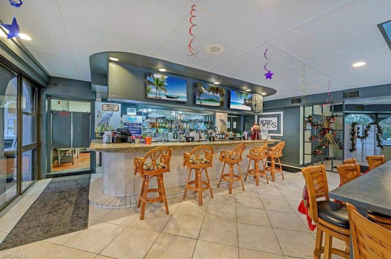 A bar area with a counter, bar stools, and a seating area with tables and chairs.