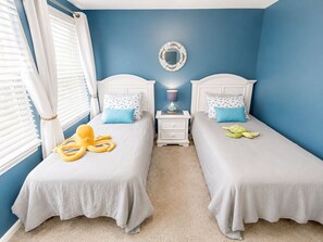 A bedroom with two beds, a nightstand with a lamp, and a decorative mirror on the wall. - Wildwood Crest Condo 1 Block from the Beach (Wildwood)