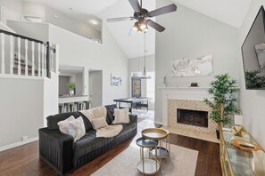 A modern living room with a black sofa, a glass coffee table, and a fireplace. - Luxe 3B Cozy and 5-Star Stay in Frisco (Frisco)