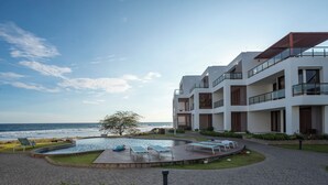 Ein modernes Gebäude mit Pool, Liegestühlen und Meerblick.