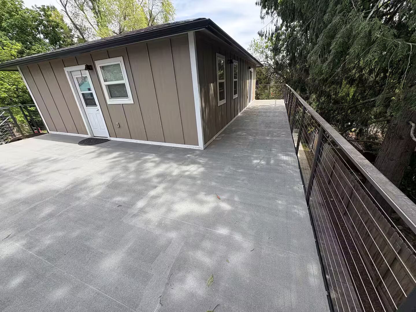 A small, single-story building with a flat roof and a concrete deck.