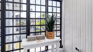 A room with a white table, a potted plant, and a window with black frames. - My Sandlot Parguera- Beach Chalet up to 16 guests (La Parguera)