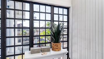 A room with a white table, a potted plant, and a window with black frames.