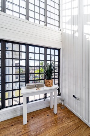 A room with a white table, a potted plant, and a window with black frames.